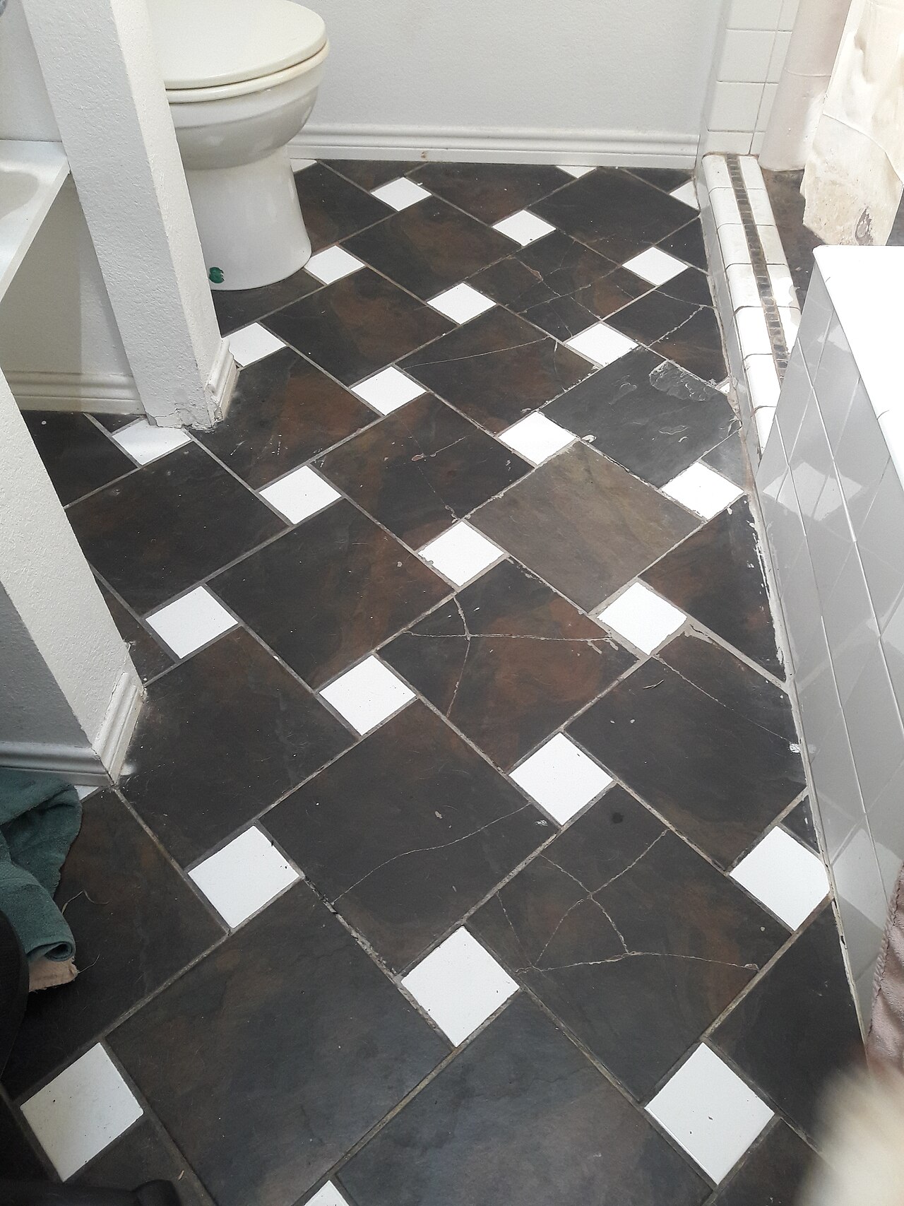 Carrelage de sol noir et blanc présentant des carreaux fissurés.