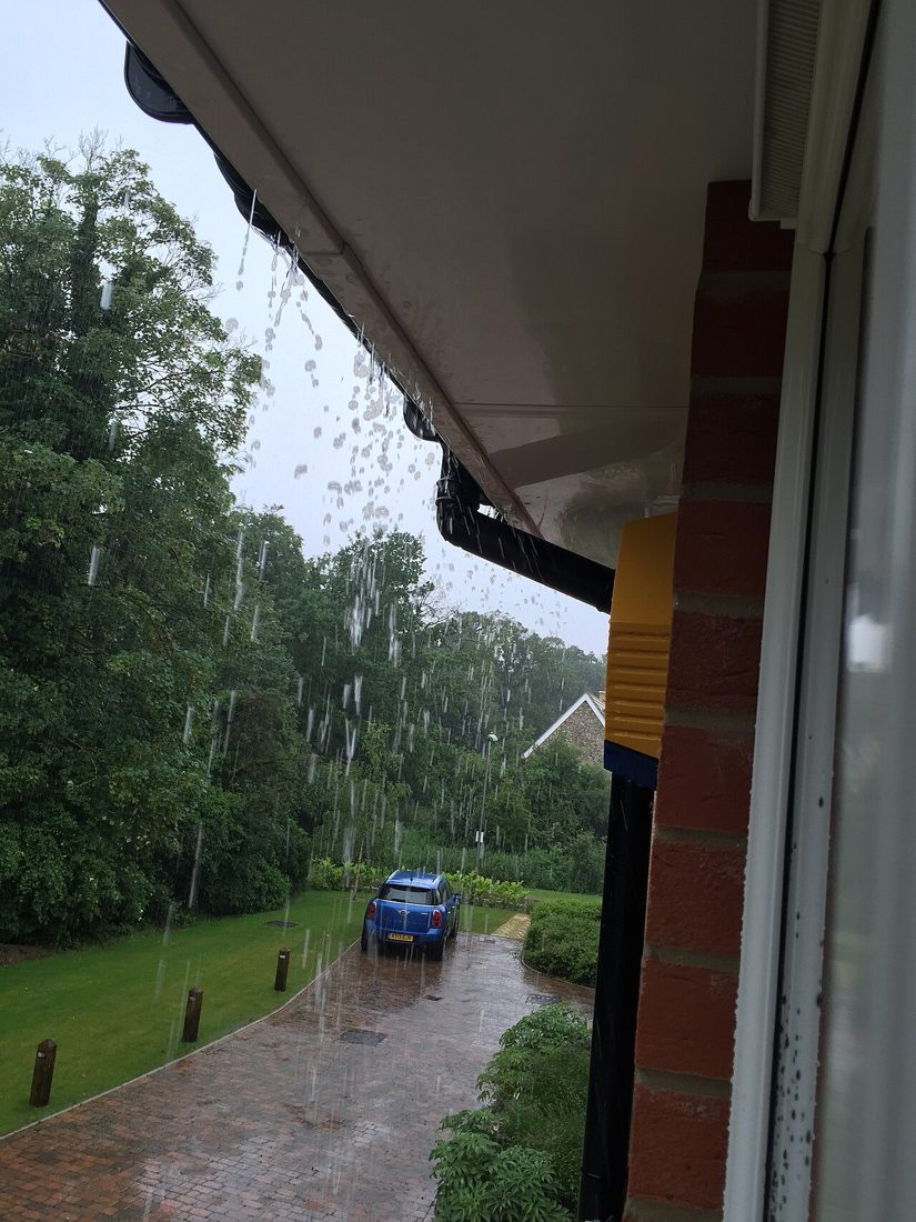 Eau de pluie qui déborde au bord d’une toiture pendant une averse