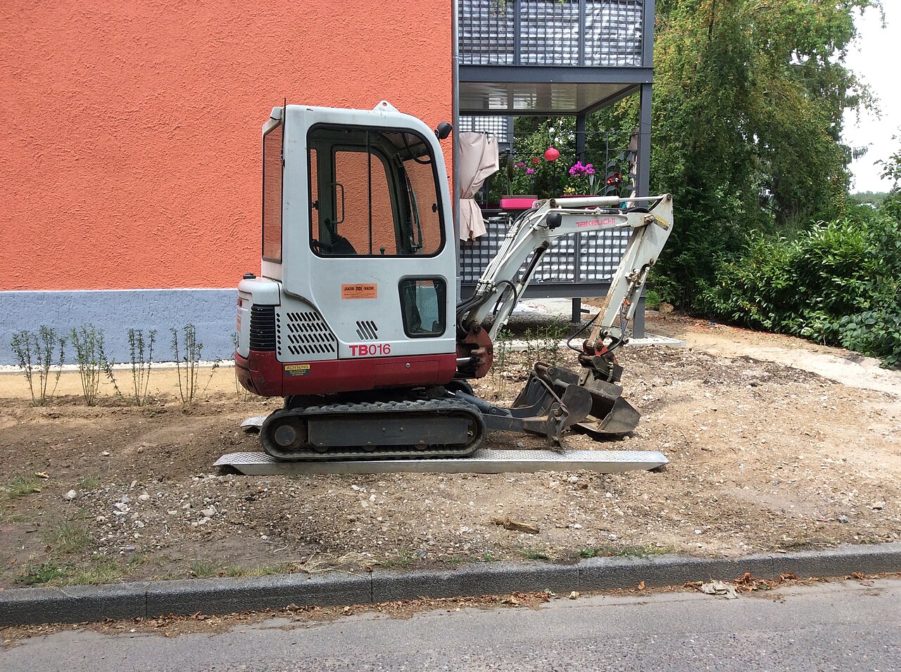Mini-pelle compacte sur chenilles stationnée sur un chantier résidentiel