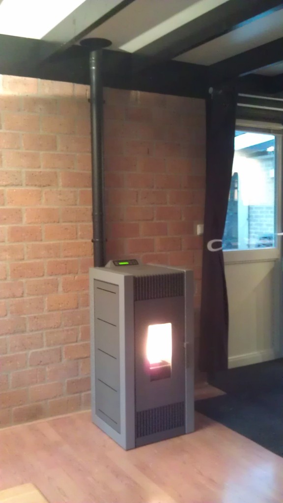 Poêle à granulés avec porte vitrée et conduit de fumée visible.