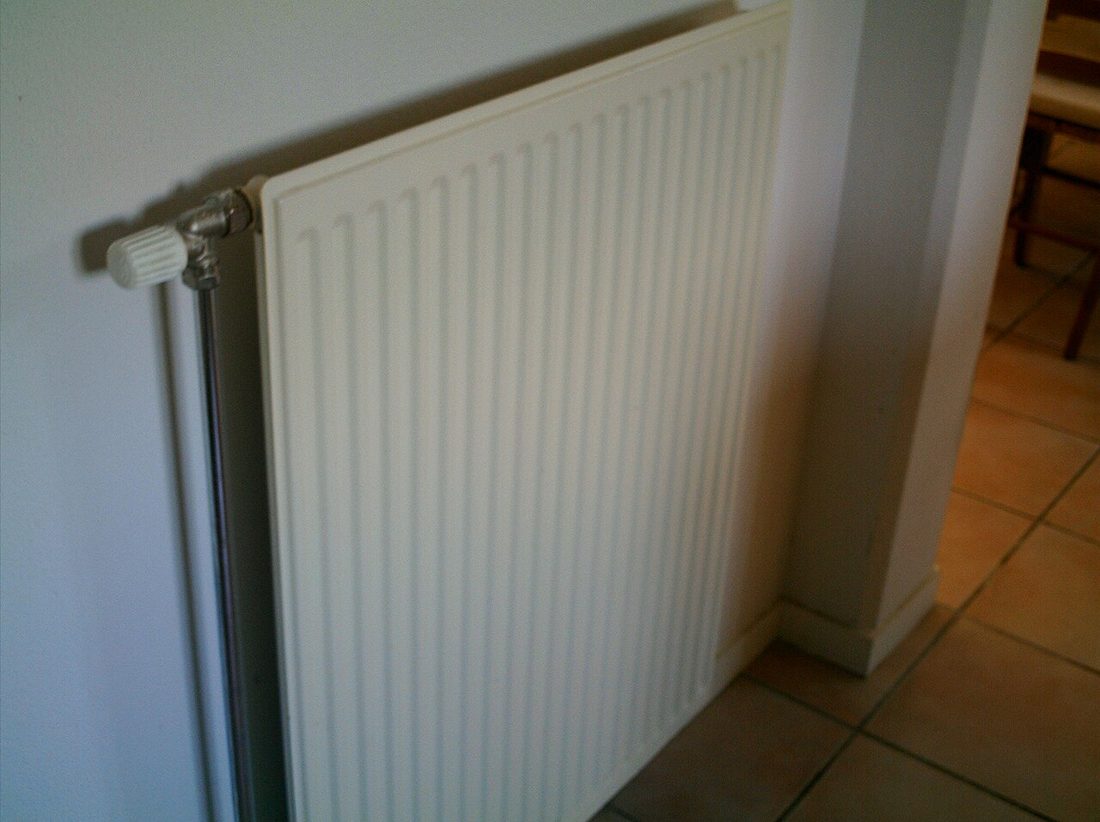 Radiateur à panneaux installé dans une pièce avec un robinet latéral visible